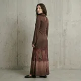 Vestido largo de satén negro con cuello alto y mangas largas. Presenta un diseño con una franja de encaje negro transparente en la parte inferior, que conecta el cuerpo de satén con una falda de satén en degradado gris oscuro.