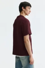Remera de punto de algodón de peso medio color bordó, con cuello redondo ribeteado, hombros caídos y bajo recto, de corte relajado.