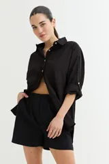 Camisa color crudo, de corte clásico, con cuello camisero, cierre frontal con botones y mangas 3/4 con trabillas.