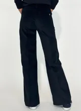 Pantalón de corte recto y tiro medio, confeccionado en pana color bordó. Presenta costuras verticales decorativas en el frente, cierre con botón y bolsillos laterales.