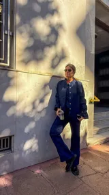 Camisa de jean azul oscuro con cuello redondo, cierre frontal de botones y mangas abullonadas con puños ajustados.