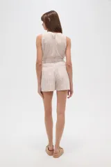 Short de tiro alto con diseño de rayas verticales en tonos beige y blanco. Presenta una cintura elástica con detalle de volado y cordón ajustable para atar al frente. Su corte es holgado y cómodo.