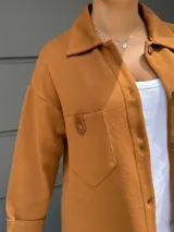 Camisa de punto color naranja quemado, con cuello camisero, botones frontales y bolsillos de parche en el pecho.