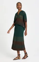 Pollera midi de punto con diseño calado, en combinación de colores verde y marrón, de corte recto y tiro alto.