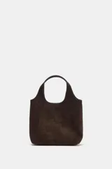 Bolso formato mini shopper confeccionado en piel de color marrón oscuro. Cuenta con doble asa de mano, asa bandolera extraíble, bolsillo interior con cremallera y cierre mediante botón imantado.