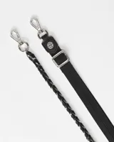 Bandolera porta celular negra con diseño acolchado, correa larga de cinta y cadena metálica decorativa.