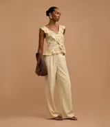 Pantalón de vestir de mujer, tiro alto, corte wide leg, color beige claro. Presenta pliegues frontales y frisos marcados.