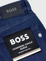 Jeans de corte ajustado en denim azul oscuro, con etiqueta de la marca Boss cosida en el bolsillo trasero y remaches metálicos grabados.