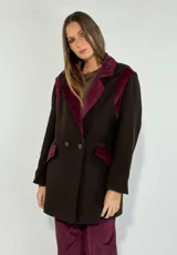 Tapado de paño de lana color marrón oscuro, con solapas, detalles en los hombros y solapas de bolsillos en pana color bordó. Presenta cierre frontal cruzado con botones.