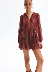 Vestido corto de manga larga confeccionado en tejido transparente, con estampado estilo paisley en tonos borravino y rosado. Presenta cuello redondo con abertura frontal y cordones para atar, cintura elástica y falda con volados en capas.