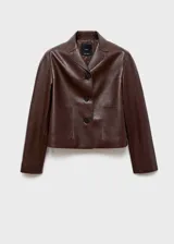 Chaqueta corta de efecto piel en color marrón chocolate, con cuello camisero, cierre frontal con botones y dos bolsillos de parche delanteros.