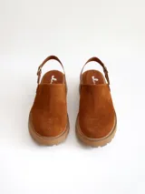 Zueco de cuero gamuzado color óxido, con tira trasera ajustable mediante hebilla metálica. Presenta una suela de plataforma con textura acanalada y detalle de textura reptil en la tira posterior.