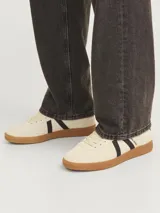 Championes de diseño urbano, color beige con franjas laterales negras y suela de goma marrón.