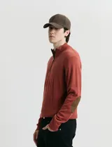 Sweater de punto color verde oliva, con cuello alto y medio cierre frontal. Presenta coderas en símil nappa y puños acanalados.