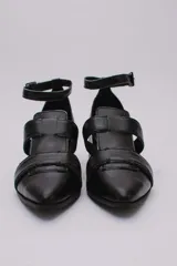 Sandalias plateadas con punta cerrada, tiras entrecruzadas y pulsera al tobillo con hebilla. Taco cuadrado negro.