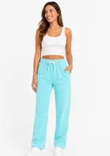 Pantalón de felpa color turquesa, de corte recto y holgado, con cintura elástica y cordón ajustable. Cuenta con bolsillos laterales.