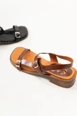 Sandalias negras de cuero con diseño de tiras rectas, hebillas metálicas y un mini taco de 1.5 cm. La suela tiene detalles de tachas pequeñas.