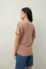 Remera negra de manga corta, confeccionada en modal, con cuello bote y frunces laterales.