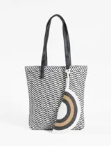 Bolso tipo canasto de playa con patrón bicolor blanco y negro. Tiene asas de cuero sintético negro y un estuche removible con cierre.