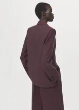 Blazer de diseño recto estilo traje, color bordó, confeccionado en tejido de lyocell. Cuenta con cuello pico con solapa de muesca, manga larga con puños abotonados, dos bolsillos laterales con solapa y cierre frontal de un botón.