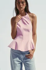 Top rosa claro, entallado, con cuello halter que se abrocha en la nuca y espalda descubierta. El bajo tiene un corte peplum acampanado.