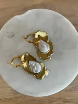 Aros tipo argolla con dije de bronce reticulado de forma irregular y piedra engarzada en el centro. Diseño artesanal con acabado texturizado.