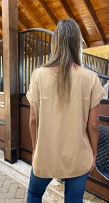 Blusa de satén color beige con cuello redondo, mangas cortas con dobladillo y corte holgado. La parte trasera está confeccionada en algodón con lycra para mayor comodidad y movilidad.