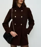 Campera de paño color marrón, con diseño estructurado de doble abotonadura con seis botones metálicos dorados. Presenta cuello alto, mangas largas y corte recto.