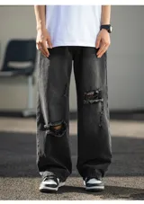 Jean de corte ancho y holgado, color negro lavado con efecto desgastado y roturas visibles en la parte delantera de las piernas. Presenta cinco bolsillos.