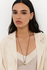 Colgante con cadena fina negra y dije dorado con forma irregular.