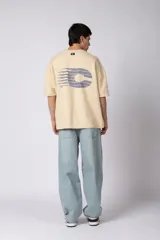 Remerón de corte oversized confeccionado en tejido rústico, con cuello redondo y mangas cortas. Presenta un diseño minimalista con una pequeña estampa frontal centrada en el pecho.