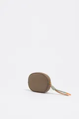 Monedero de forma ovalada marca Bimba y Lola, confeccionado en nylon color beige con detalles en verde oliva en el cierre y logo metálico dorado en el frente.