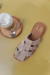 Sandalias de cuero con diseño de tiras entrelazadas, estilo jaula, con suela plana y cierre de hebilla lateral.