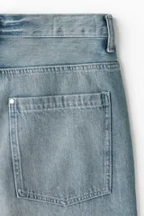Jeans de cinco bolsillos en denim de algodón rígido, color celeste claro con efecto desgastado/lavado. Modelo de corte super holgado (baggy) desde la cadera hasta el tobillo, con piernas redondeadas extraamplias y tiro bajo.