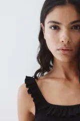 Musculosa corta negra de ajuste entallado en punto acanalado de algodón. Modelo con breteles y escote cuadrado con ribete de volado efecto arrugado que se prolonga por los hombros.