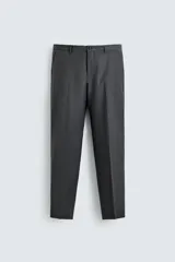 Pantalón de traje regular fit color gris oscuro, confeccionado en tejido con lana, con bolsillos frontales y bolsillos traseros de doble vivo con botón. Cierre frontal con cremallera y botón.