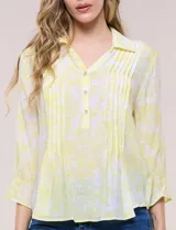 Blusa celeste con estampado efecto pincelada blanca, de corte semi holgado, escote en V con cuello solapa y media abotonadura frontal con botones nacarados. Presenta finas alforzas verticales en la pechera y mangas 3/4 con puños elastizados.