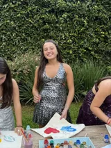 Vestido corto negro con estampado de plumas doradas, escote en V, breteles finos cruzados en la espalda, cut-outs laterales y volado en el ruedo.