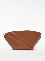 Bolso de hombro Adolfo Dominguez modelo Eclipse, confeccionado en piel bovina color tostado. Presenta un diseño estructurado formado por dos piezas asimétricas entrecruzadas, cierre con cremallera, asa de hombro extraíble y logo grabado en la parte frontal.