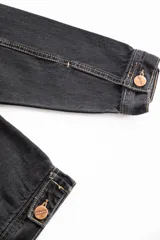 Campera corta de jean negro con cuello de pana marrón, confeccionada en jean grueso 100% algodón de 14 onzas, con costuras marrones en contraste.
