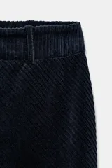 Falda midi de tiro alto confeccionada en tejido de pana, con corte recto, trabillas en la cintura y abertura frontal en el bajo. Cuenta con cierre de cremallera oculta en la espalda.