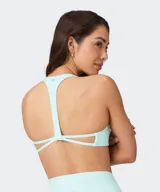 Top deportivo Fabletics modelo PureLuxe color verde militar, con diseño cruzado en la parte delantera y tirantes halter.