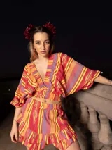 Conjunto de dos piezas compuesto por un top corto de mangas abullonadas con elástico y una falda corta con volados, ambos confeccionados en tela estampada a rayas multicolores.