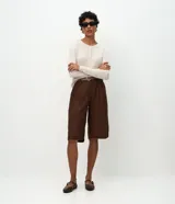 Cardigan de punto canelado color verde oliva, con cuello redondo, manga larga y cierre frontal abotonado.