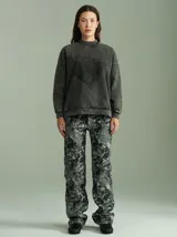 Pantalón de corte recto y tiro medio-alto, confeccionado en algodón grueso con apariencia de denim. Presenta un estampado abstracto en tonos grisáceos y negros, con bolsillos delanteros y traseros.