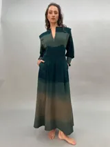Vestido largo verde con efecto degradado, mangas largas abullonadas y falda con tajos laterales.