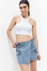 Minifalda de jean celeste con diseño asimétrico, bolsillos de parche con solapa y tiras ajustables con hebillas en los laterales.