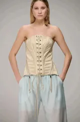 Corset strapless color beige con diseño estructurado, cordones frontales y cierres laterales con tiradores colgantes.