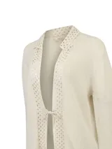 Cardigan abierto de punto color beige con cuello y ribetes frontales de encaje tejido al crochet y cierre con lazo delantero.