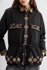 Campera estilo militar (army) color negro, con calce recto y ajuste interno en la cintura mediante cordón con borlas. Presenta bordados con apliques de lentejuelas en el cuello, bolsillos frontales y puños.